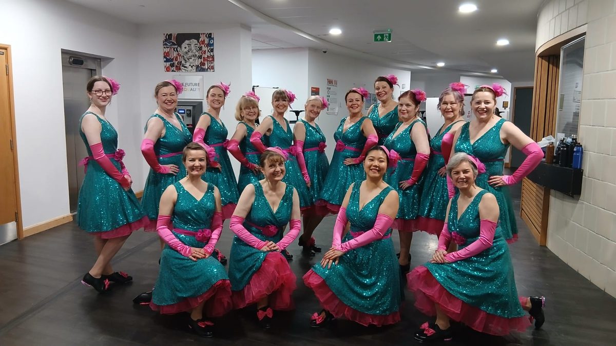 The adult tap group in teal and pink costumes