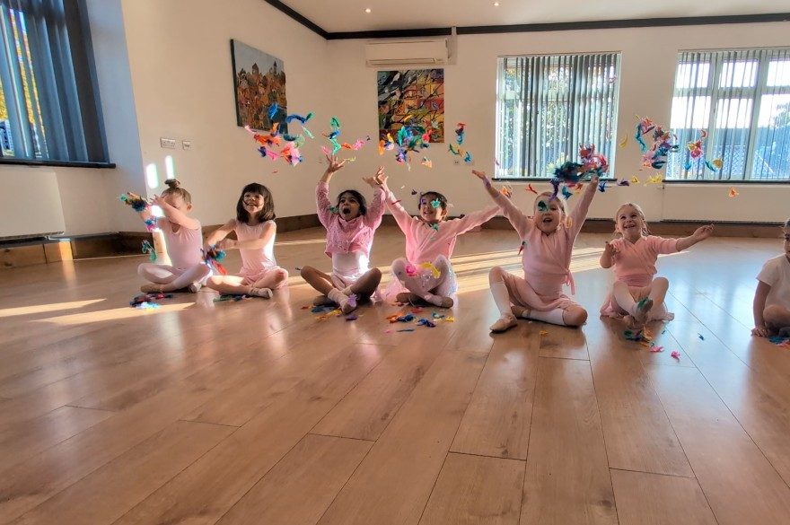 Pre-primary ballet class sitting on the floor throwing coloured streamers